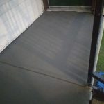 A freshly poured concrete porch showing smooth surface textures and surrounding features.